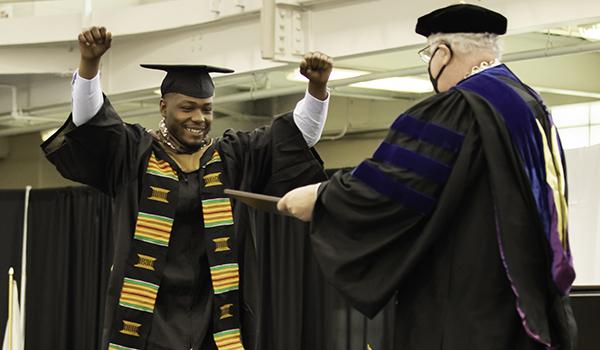 一名毕业生在拿到文凭前将双臂高举在空中